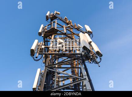 Ein Kommunikationsturm mit Mobilfunkantennen vor blauem Himmel. Stockfoto