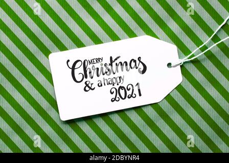 Label mit englischer Kalligraphie Frohe Weihnachten und EIN glückliches 2021. Grünes Geschenkpapier Als Hintergrund Stockfoto