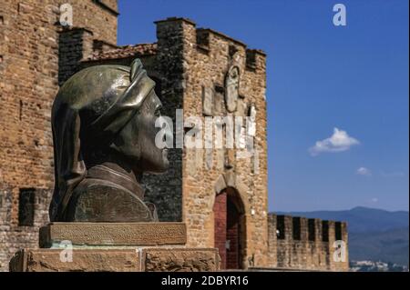 Bronzebruste des italienischen Dichters Dante Alighieri (ca. 1265-1321) am Munition Tower oder Antiporta della Munizione der mittelalterlichen Burg der Guidi-Grafen oder Castello dei Conti Guidi in Poppi, Toskana, Italien. Dante kämpfte 1289 bei der nahe gelegenen Schlacht von Campaldino um die siegreichen Florentiner. Die Burg Poppi wurde um 1274 erbaut. Der Munition Tower (im Hintergrund) wurde in den 1400s Jahren als äußere Verteidigung hinzugefügt. Stockfoto