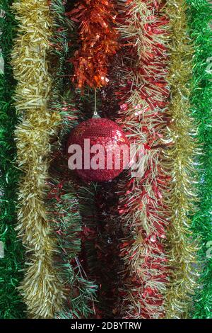 Glänzende Weihnachtskugel mit Glitzer und buntem Lametta Hintergrund. Dekoration für Weihnachten. Stockfoto