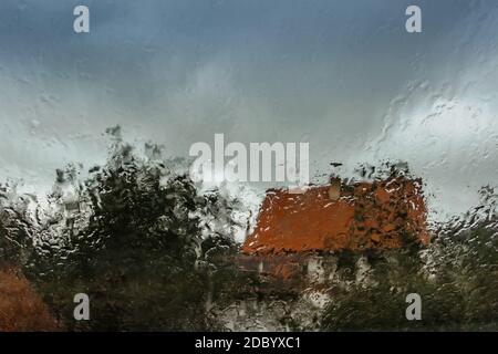 Tropfen auf Glas in regnerischen Tag.Regen Außenfenster in der Landschaft. Textur von Regentropfen, nasses Glas.regnerischer Fensterhintergrund.Blick durch das Fenster Stockfoto