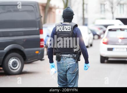 18. November 2020, Berlin: Ein Polizist läuft auf der Straße. Die Berliner Polizei durchsuchte Räume eines islamischen Kulturvereins in Neukölln und eine Wohnung. Ein 35-jähriger Mann wird wegen des Verdachts auf Subventionsbetrug untersucht, sagte eine Sprecherin. Der Mann soll im April ungerechtfertigt 5000 Euro in Corona-Soforthilfe beantragt haben. Foto: Annette Riedl/dpa Stockfoto