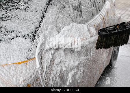 Auf dem Auto Seite Spiegel komplett mit Seife Schaum bedeckt Detail, mehr Sprühen von Bürste, wenn in der Waschstraße gewaschen. Stockfoto