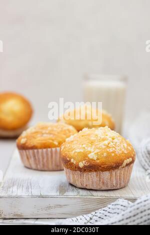 VanilleMuffins und Muffins mit Streusel in Pappbechern mit einem Glas Milch. Frühstück oder Snack für Kinder. Stockfoto