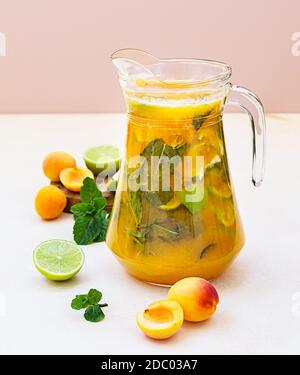 Aprikosencocktail oder Eistee mit frischer Minze, Limette und Aprikosen. Erfrischendes kaltes Getränk im Sommer. Heller Hintergrund. Stockfoto
