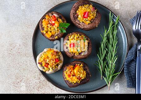 Gebackene gefüllte portobello-Pilze mit Bulgur-Pilaf und gehacktem Gemüse. Leckeres und nahrhaftes vegetarisches Gericht. Draufsicht. Stockfoto