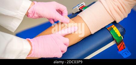 Nahaufnahme der Schwesternhand, die Klebstoff auf dem Arm aufgibt Des Patienten nach der Blutentnahme im Krankenhaus Stockfoto