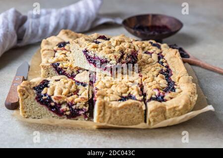Hausgemachte Mürbeteig Beeren Marmelade Kuchen auf Backpapier, heller Hintergrund. Zerbröseln Sie den Kuchen. Stockfoto
