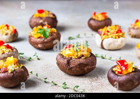 Gefüllte portobello-Pilze mit Bulgur, Gemüse und aromatischen Kräutern auf betontem Hintergrund. Vegetarisches Essen. Stockfoto