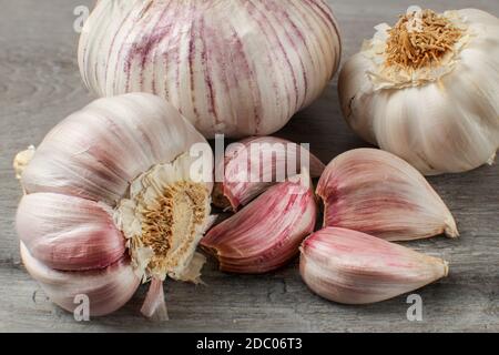 Detaillierte Foto von Knoblauch Zwiebeln und rotem Purpur Nelken auf Grau woode Tabelle. Stockfoto