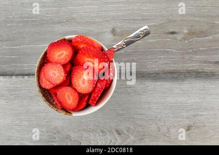 Table Top Blick auf kleinen Schüssel Himbeeren in kleine Stücke geschnitten, mit silbernen Löffel - bereit, gesunden Snack zu essen. Stockfoto