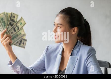 Erfolgreiche asiatische Business junge Frau hält Geld US-Dollar-Scheine in der Hand auf Schreibtisch, Business Finance Konzept Stockfoto