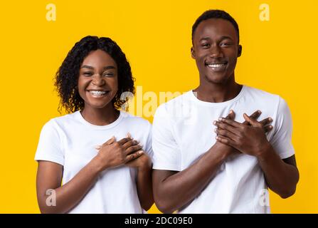 Freundliche afrikanische Frau und Mann halten beide Handflächen auf der Brust Stockfoto