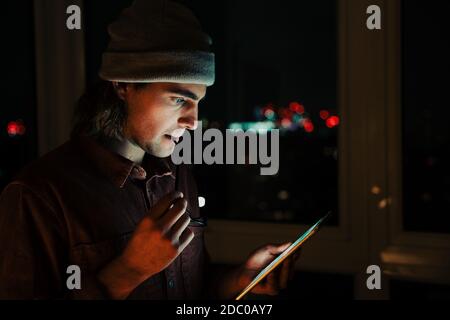 Kaukasischen Geschäftsmann E-Mails auf digitalen Tablet zu überprüfen arbeitet spät In der Nacht in der Wohnung Stockfoto
