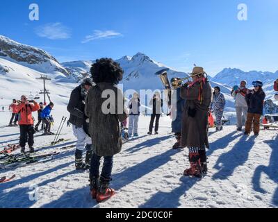 Musikkapelle in Karnevalskostümen und Skifahrer versammelten sich in Idalp, Skigebiet Ischgl, Österreich Stockfoto