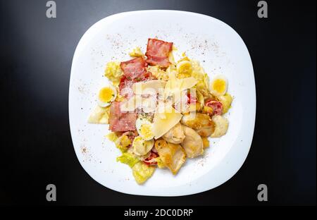 Caesar Salat in flachem Lay.Delicious Snack Food mit gegrilltem Huhn Fleisch auf weißem Keramikteller serviert, direkt von oben geschossen Schwarzer Hintergrund Stockfoto