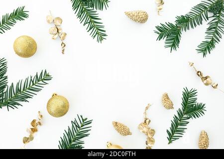 Weihnachtsrahmen aus immergrünen Ästen und goldener Dekoration auf weißem Hintergrund. Flach liegend, Draufsicht Stockfoto