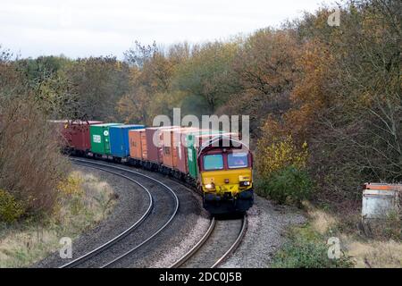 EWS Baureihe 66 Diesellokomotive Nr. 66133 zieht einen freightliner Zug im Herbst, Warwickshire, UK Stockfoto