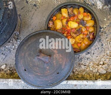 Langsames Kochen in Gusseisen Topf bei Kohlen Feuer Stockfoto