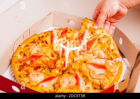 Heißes hausgemachtes, vegetarisches fast italienisches Essen, Hand von Little Child Holding Delivery Pizza Pepperoni, Käse viele Scheiben in einem offenen Karton Stockfoto