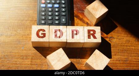 GDPR Wort in Holzwürfel und Rechner auf Holztisch geschrieben. Stockfoto