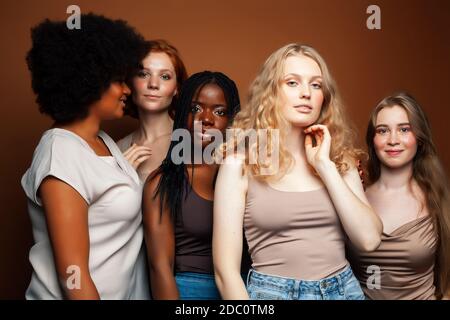 Junge hübsche kaukasische, afro, skandinavische Frau posiert fröhlich zusammen auf braunem Hintergrund, Lifestyle diverse Nationalität Menschen Konzept Stockfoto