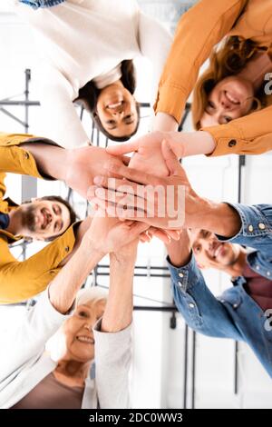 Grundansicht multikultureller Menschen, die Hände halten und lächeln Kamera auf unscharfem Hintergrund Stockfoto