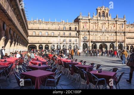 Salamanca Plaza Mayor mit Cafétischen und Stühlen draußen und Gruppen von Menschen zu Fuß an einem sonnigen Wintertag über Weihnachten, Kastilien und Leon, Spanien Stockfoto
