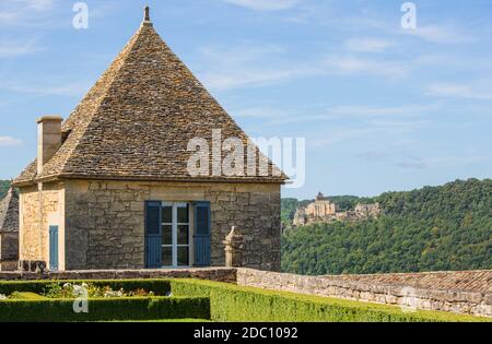 Formgehölze in den Gärten des Jardins de Marqueyssac in der Region Dordogne in Frankreich. Burg von Castelnaud auf der Rückseite. Stockfoto