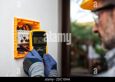 Elektriker bei der Arbeit mit dem Tester misst die Spannung in der elektrischen Zentrale einer Wohnanlage. Bauindustrie. Stockfoto