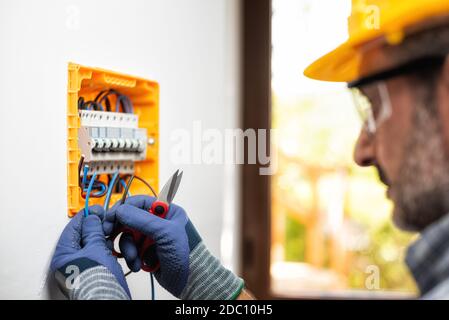 Elektriker bei der Arbeit bereitet elektrische Kabel in der Schalttafel einer elektrischen Wohnanlage vor. Bauindustrie. Stockfoto