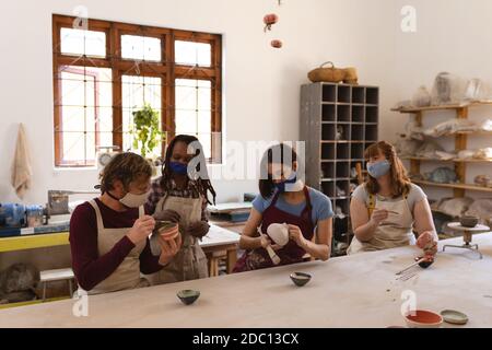 Multi-ethnische Gruppe von Töpfern in Gesichtsmasken arbeiten in Keramik studio Stockfoto