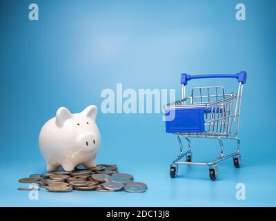 Ein Warenkorb mit einem Haufen Münzen und Sparschwein auf blauem Hintergrund. Hypothekenkonzept. Geld und Haus. Finanzstatus. Stockfoto