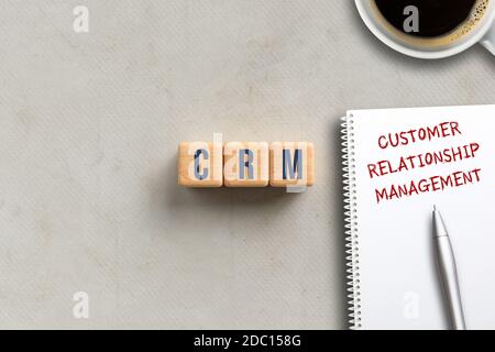 Akronym CRM auf Würfel und Notizblock mit Erklärung KUNDENBEZIEHUNG MANAGEMENT auf Papier Hintergrund Stockfoto