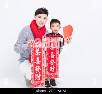 Glücklicher asiatischer Vater und Sohn, der rote Umschläge zeigt und Neujahr feiert. chinesischer Text: Herzlichen Glückwunsch zum chinesischen Neujahr Stockfoto