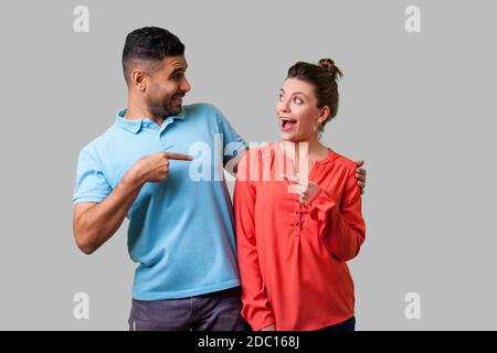 Portrait von überrascht junges Paar in Freizeitkleidung stehend mit geöffnetem Mund, umarmen, als Freunde, zeigen und sich einander schockiert. Stockfoto