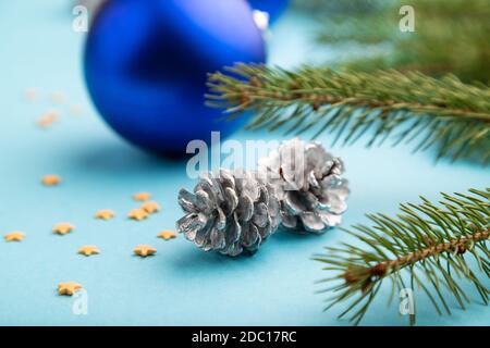 Komposition zu Weihnachten oder Neujahr. Dekorationen, blaue Kugeln, Zapfen, Tanne und Fichte Äste, auf einem blauen Papier Hintergrund. Seitenansicht, Nahaufnahme, selektiv Stockfoto