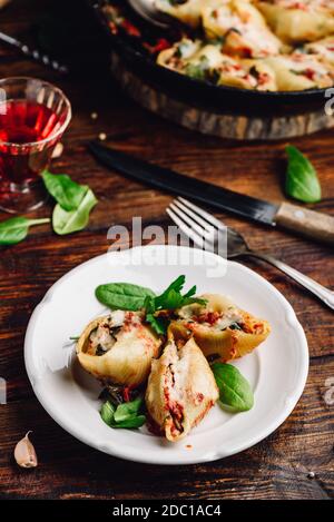 Gebackene Jumbo Shells Pasta gefüllt mit Hackfleisch, Spinat und Käse auf weißem Teller Stockfoto