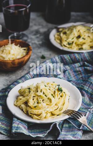 Portionen hausgemachte Pasta Alfredo auf weißem Teller mit geriebenen Käseschale Stockfoto