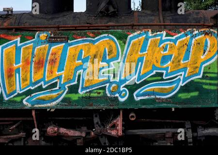 ‘Hilfe’ und ‘Hilfe’ zweisprachige Bitten in Deutsch und Englisch farbenfrohe Spraydose-Graffiti auf einer rostigen Dampflokomotive, die 2008 auf die Restaurierung an der ehemaligen Nordosttermine in Heidenreichstein, Gmünd, Niederösterreich, der Waldviertelbahn oder der Waldviertler Schmalspurbahn wartet. Die Eisenbahn ist ein ehemaliges industrielles 760 mm Schmalspurnetz, das heute von der Provinzregierung und Enthusiasten als Kulturattraktion erhalten und betrieben wird. Stockfoto