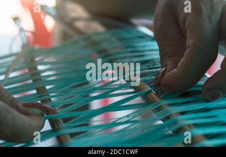 Frau an der Webmaschine für Weben handgemachten Stoff. Textil Weberei. Das Weben mit traditionellen Webstuhl auf Baumwolle Fasern. Textil- oder Stockfoto