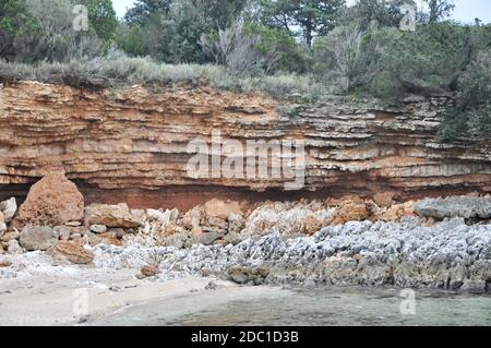 Abstrakte rote Klippe am kroatischen Strand, Holz aus der Adria. Strand Hintergrund. Abstrakt verwitterte Felsen am Sandstrand. Stockfoto