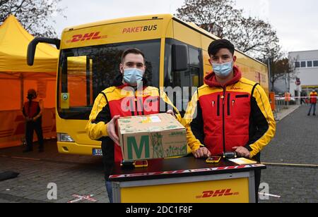 Berlin, Deutschland. November 2020. Zwei DHL-Mitarbeiter halten während einer Presse- und Fotositzung an der Abnahmestelle des DHL-Paketbusses ein Paket zur Präsentation der Busse. An mehreren Berliner Standorten stehen die Busse Bürgern als DHL Paketshops zur Verfügung. Quelle: Britta Pedersen/dpa-Zentralbild/dpa/Alamy Live News Stockfoto