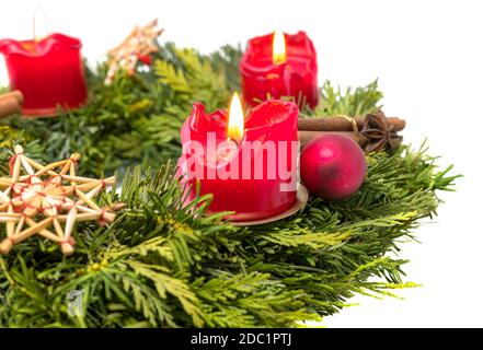 Dekorierter Adventskranz aus Tannenzweigen mit brennendem Rot Kerzen isoliert auf weiß Stockfoto