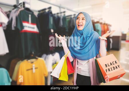 Glücklich schöne junge Frau Muslim lächelnd lustig tragen Schleier Hijab sie aufgeregt halten Einkaufstaschen Multi Farbe auf dem Mall Hintergrund mit Kopieplatz, Stockfoto