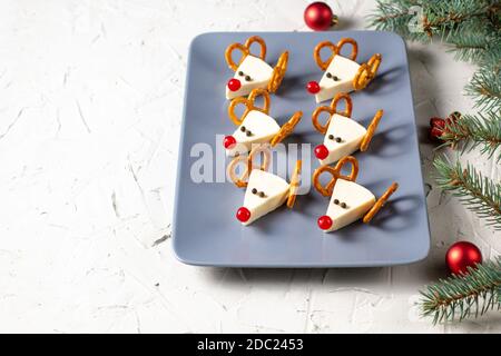Lustige weihnachts-Snack in Form von Hirschen für Kinder Party. Konzept Neujahrskost aus Käse und Brezeln auf weißem Hintergrund Stockfoto