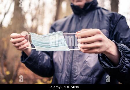 Mann, der eine medizinische Maske aufsetzt, um vor dem Corona-Virus zu schützen. Einweg-Gesichtsmask. Junge Person im Begriff, Coronavirus-Schutz zu tragen. Covid-19-Infektion. Stockfoto