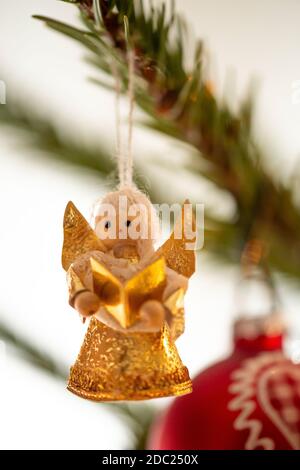 Geschmückter Weihnachtsbaum, echte Nordmann-Tanne vor verschwommenem Hintergrund. Makrofotografie zeigt einen goldenen Engel aus Holz und Papier. Stockfoto