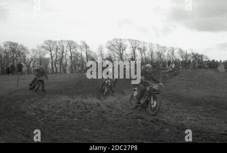 Ende der 1950er Jahre, männliche Konkurrenten, die an einem Motorrad-Scrambling-Event, Reiten über einen schlammigen Hang. Erfunden 1924, in Camberley, Surrey, England, waren die Fahrräder, die in den 50er und frühen 60er Jahren zum Gerangel benutzt wurden, wenig anders als die Rennräder der Zeit, mit sehr wenig Federung. Heute ist der Sport als Motocross bekannt – die französische Bezeichnung für Cross-Country-Motorradfahren – und in den USA als Supercross bezeichnet. Stockfoto