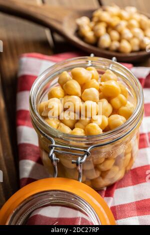 Gesunde Kichererbsen aus der Dose im Glas auf karierter Serviette. Stockfoto